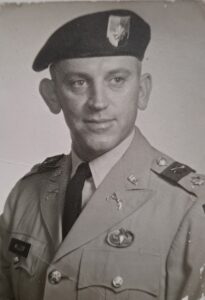 Black and white photo of man wearing green beret uniform.